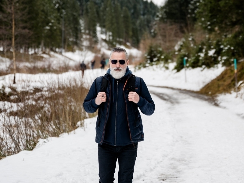 Un home amb barba caminant per un camí nevat.